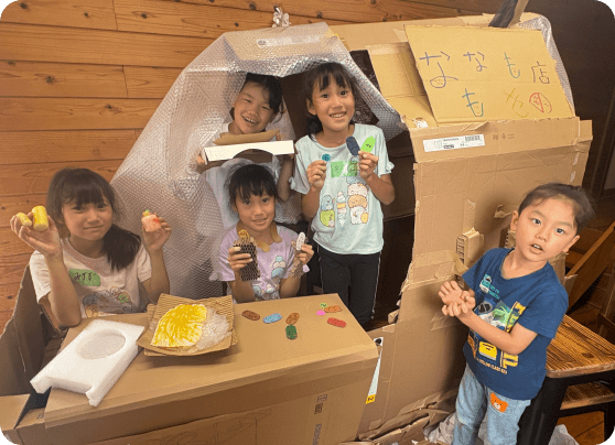 みんなで作ったダンボールの家で笑顔で遊ぶ子供たち